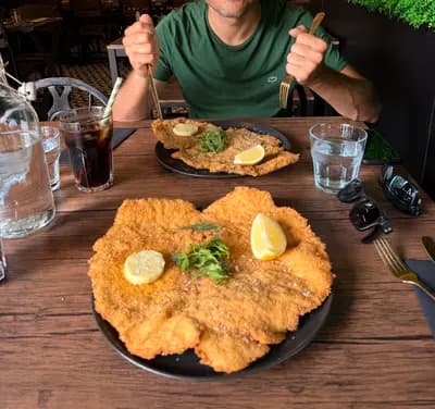 Before AI food photography: schnitzel photo with people, cluttered table, and distractions